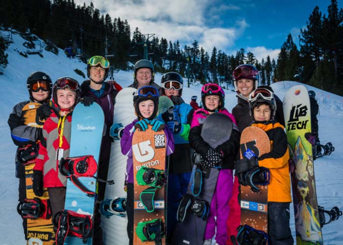 SOS Outreach youth posing with their snowboards during a trip