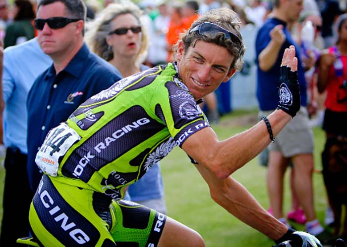 Biker racing and waving as he's going by crowds