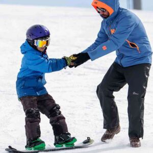 SOS mentor helping someone snowboard